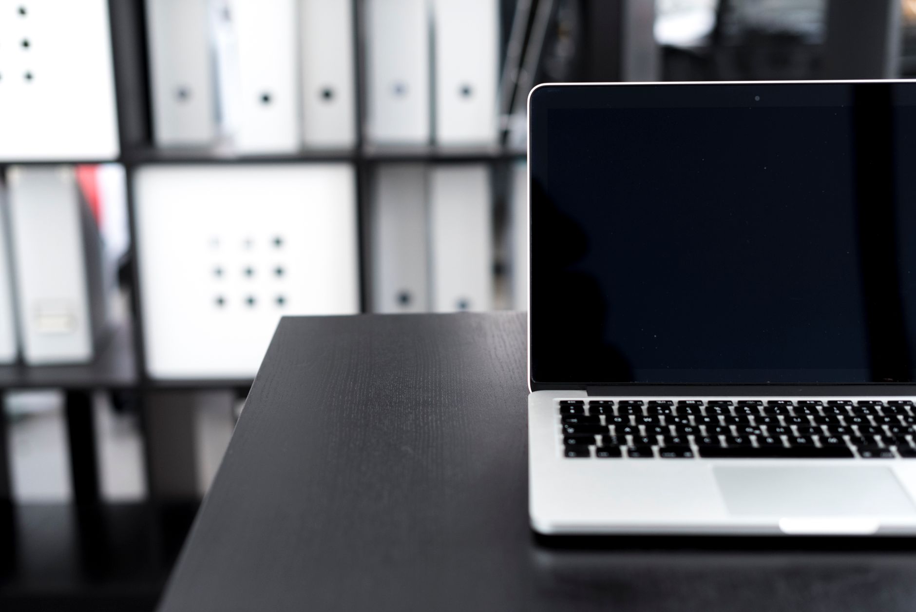 ordinateur portable fermé posé sur un bureau, classeurs de documents rangés en arrière-plan