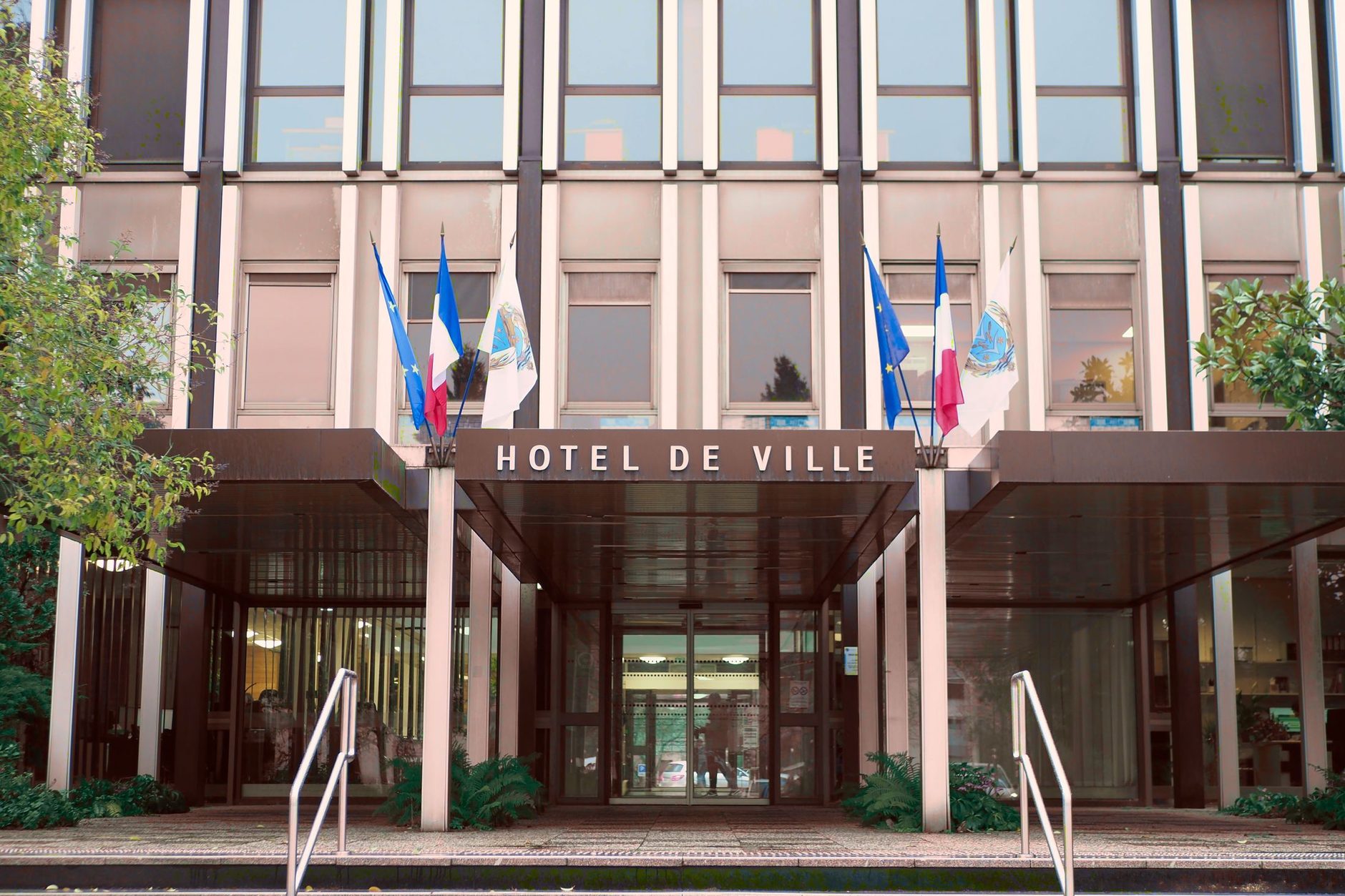 façade de l'hôtel de ville de Vélizy-Villacoublay avec ses drapeaux et une rampe d'accès devant l'entrée