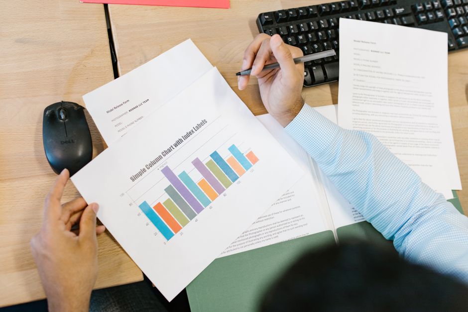 A business analyst reviews a colorful bar chart and documents at a desk, indicating data analysis.