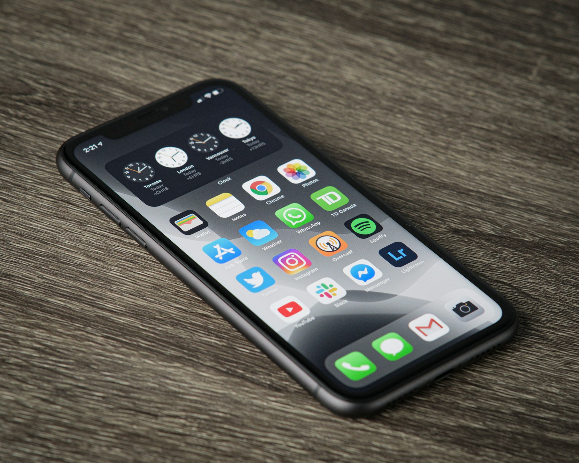 iPhone posé sur une table en bois, écran d'accueil rempli d'icônes d'applications