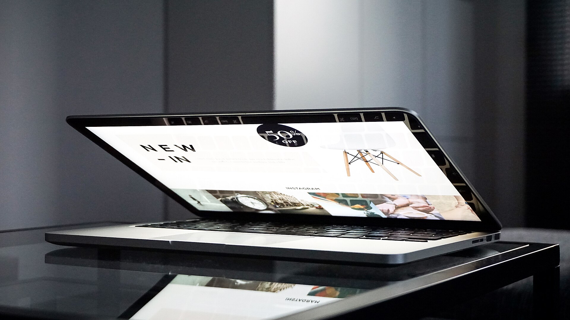 ordinateur portable entrouvert sur une table en verre, une page web affichée à l'écran